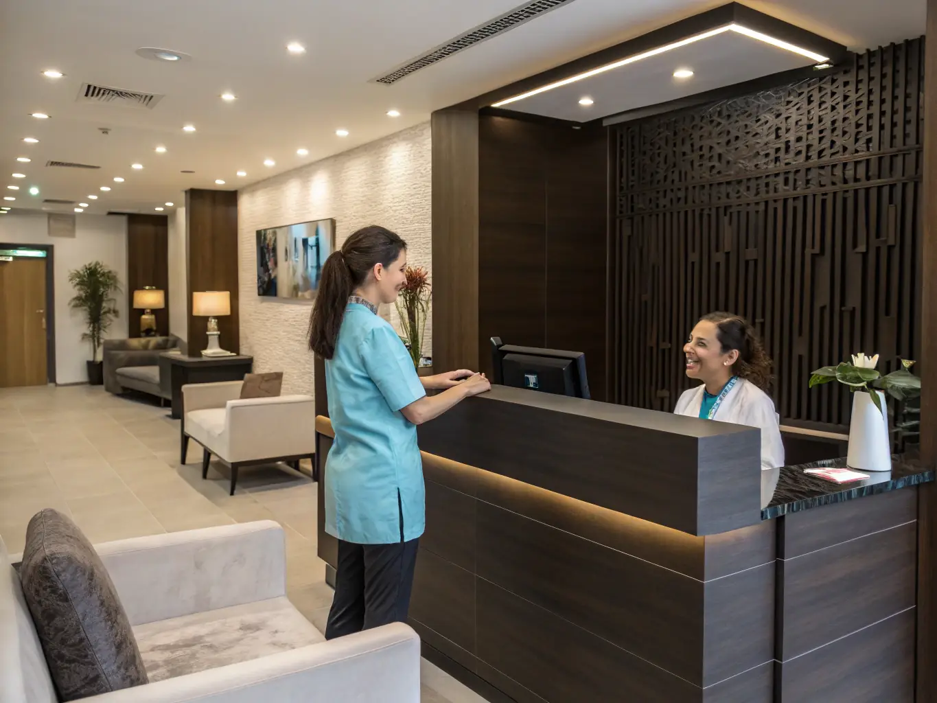 A welcoming dental clinic reception area with comfortable seating and a friendly receptionist greeting a patient, conveying a patient-oriented approach.